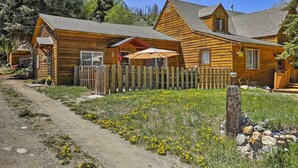 Une cabane en bois avec une véranda, une clôture en piquets et un chemin de gravier.