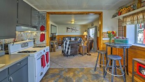 Une cuisine équipée d’une cuisinière, d’un four et de tabourets de bar. On y trouve également un coin repas avec une table et des chaises.