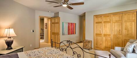 A bedroom with a bed, a ceiling fan, a nightstand, a lamp, a dresser, a chest of drawers, and a sofa.