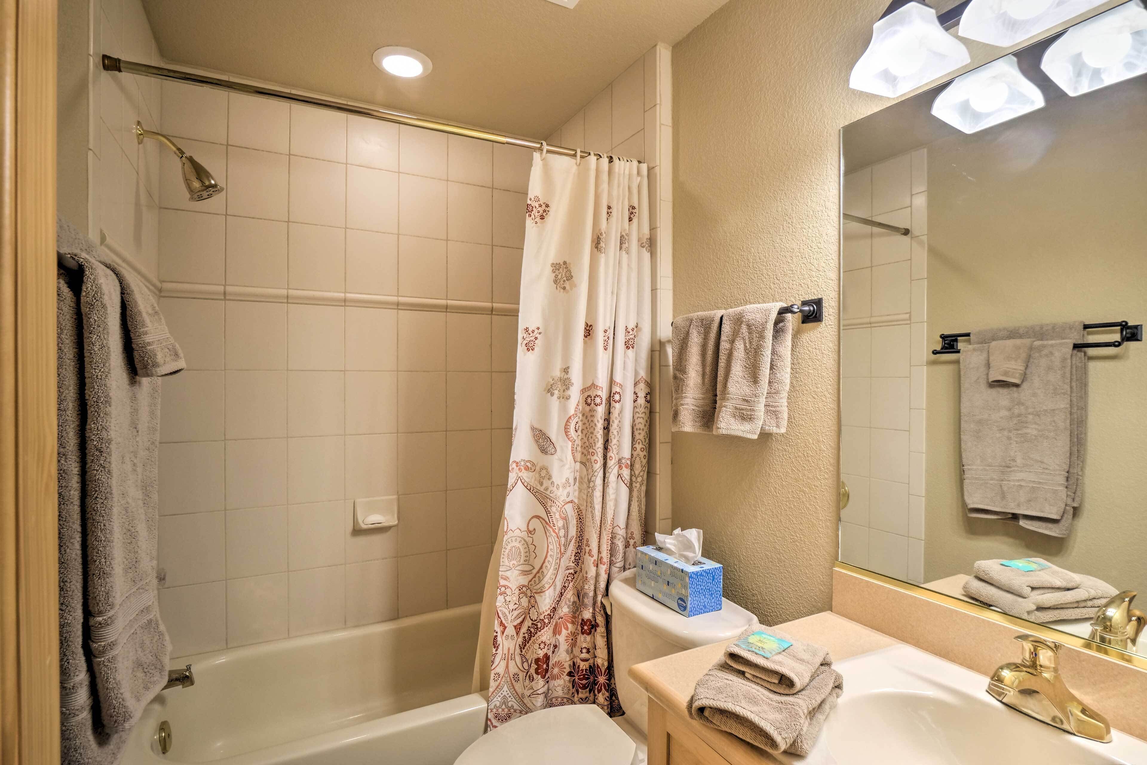A bathroom with a bathtub, toilet, sink, and a large mirror.