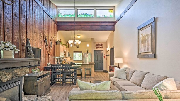 A cozy living room with a fireplace, a sofa, a dining area, and a kitchen visible through an open door. - Condo w/ Pool + Hot Tub - Walk to DT Winter Park! (Winter Park)
