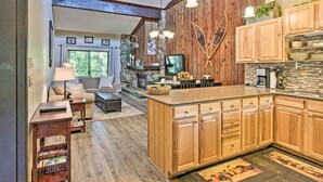 A spacious living area with a fireplace, wooden cabinets, and a large island in the kitchen. - Condo w/ Pool + Hot Tub - Walk to DT Winter Park! (Winter Park)