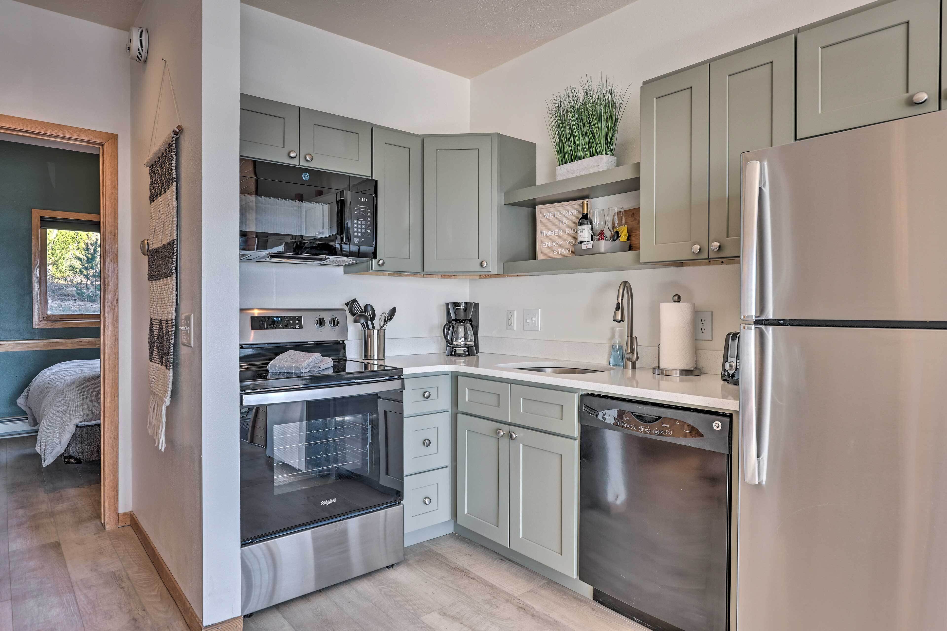A modern kitchen with grey cabinets, stainless steel appliances, and a built-in oven.