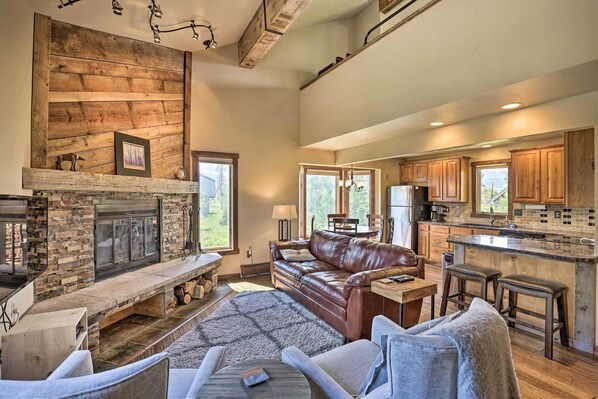 A spacious living room with a fireplace, leather sofa, and a stone fireplace surround. - 3-story Home w/ Balcony ~ 6 Mi to Winter Park! (Fraser)