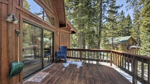 A wooden deck with a glass door leading to a room, a blue chair, and a snow-covered ground.