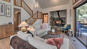 A spacious living room with a fireplace, a staircase, and a large window.