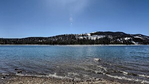 A clear lake with a forested mountain in the background.