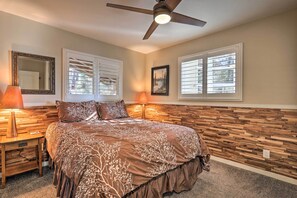 A bedroom with a wooden headboard, a bed with a floral bedspread, two bedside lamps, a ceiling fan, and two windows with blinds. - Close to Donner Lake & Skiing: Truckee Getaway (Truckee)