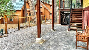 En stuga byggd av trä med en inglasad veranda, en trappa och ett inhägnat område med en bänk.