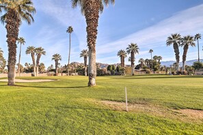 A golf course with palm trees and a clear sky.