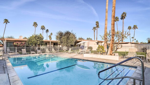 A clear blue pool with a metal ladder, surrounded by palm trees and lounge chairs. - Trendy Palm Desert Home w/ Patio & Pool Access (Palm Desert)