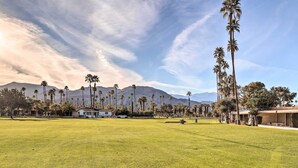 A large grassy field with tall palm trees and mountains in the background. - Trendy Palm Desert Home w/ Patio & Pool Access (Palm Desert)