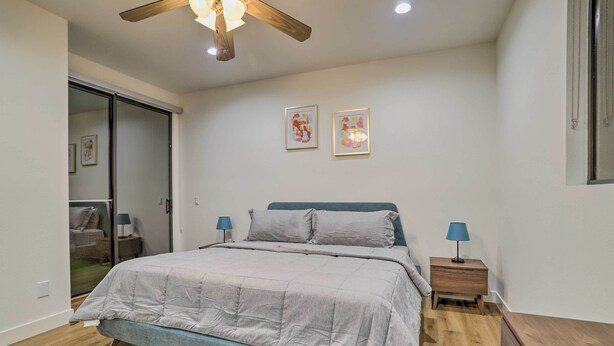 Ein Schlafzimmer mit einem Bett, zwei Nachttischen mit Lampen, einem Deckenventilator und zwei gerahmten Bildern an der Wand.