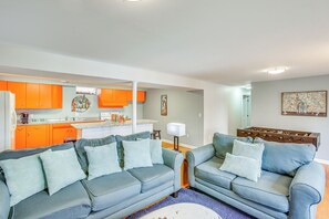 Una sala de estar con dos sofás, una mesa de centro y una zona de cocina con armarios color naranja.