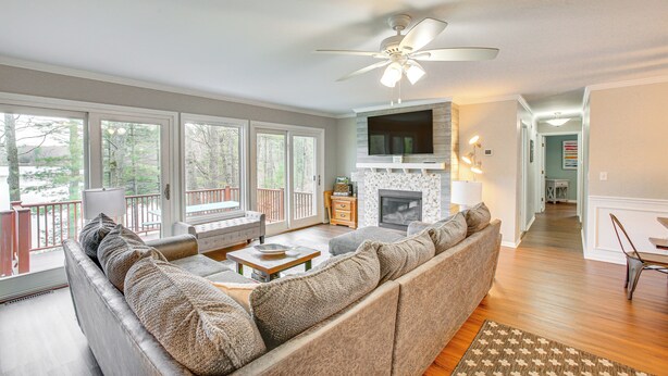 A spacious living room with a large sofa, a fireplace, and a television mounted above it. - Peaceful Lakehouse, Fire Pit, 10 Minutes to Dtwn (Traverse City)