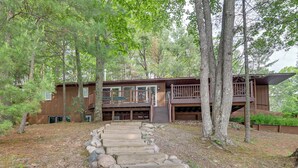 Une cabane moderne dotée d’une terrasse en bois et d’un escalier en pierre menant à l’entrée.