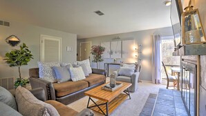 A living room with a brown leather sofa, a wooden coffee table, and a grey armchair. There is a potted plant and a wall-mounted lamp. - Ski, Shred & Tube: Mtn-view Condo in Silverthrone! (Silverthorne)