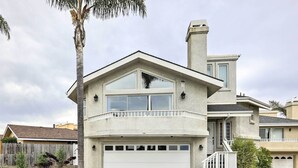 Una casa de dos pisos con garaje, balcón y chimenea.