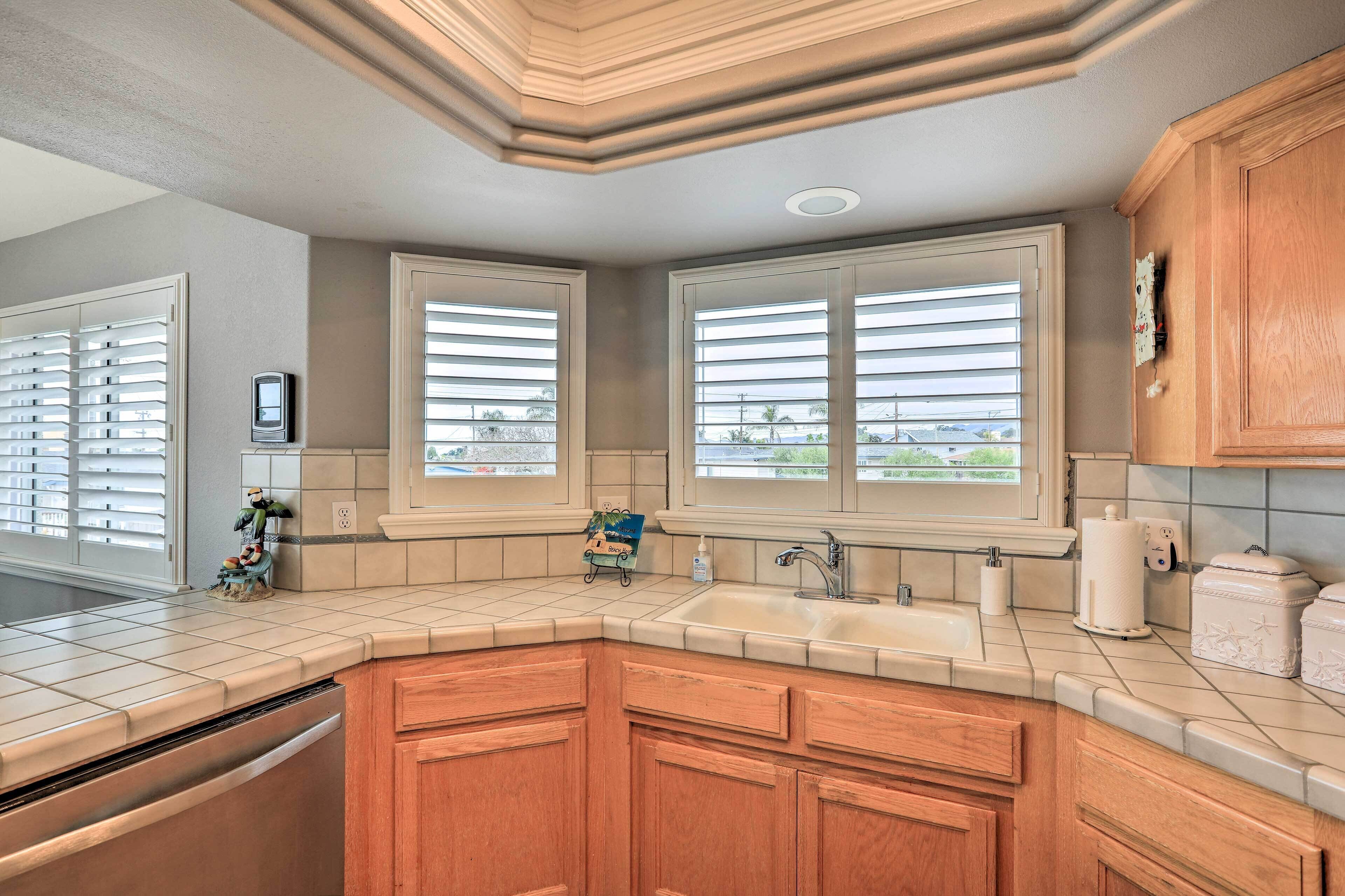 A kitchen with wooden cabinets, a built-in dishwasher, a double sink, and a window with blinds.
