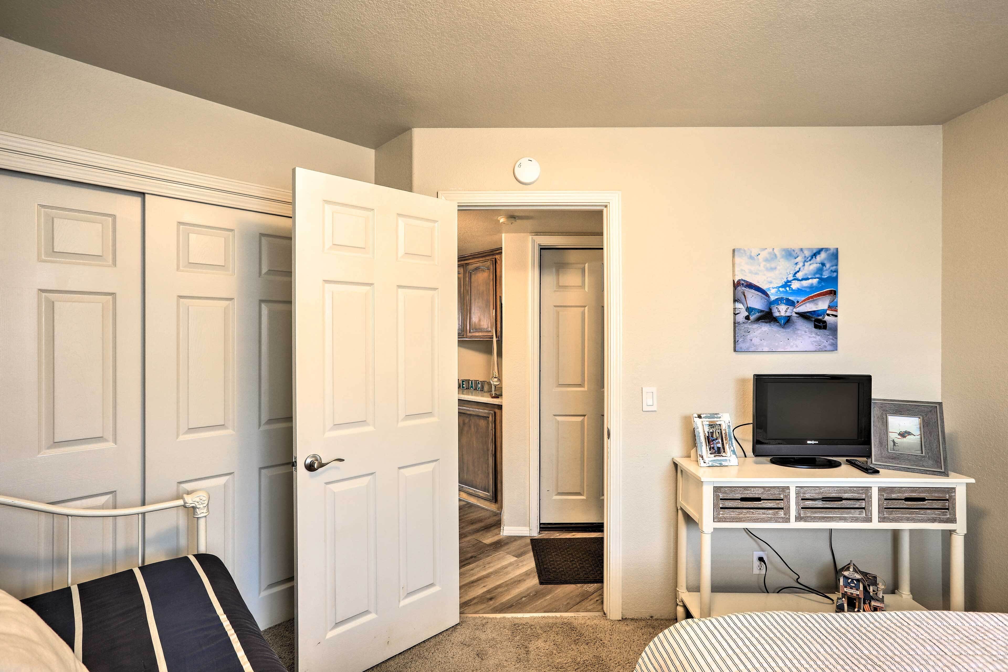 Une chambre à coucher avec un lit, un bureau avec une télévision, un tableau et une armoire.