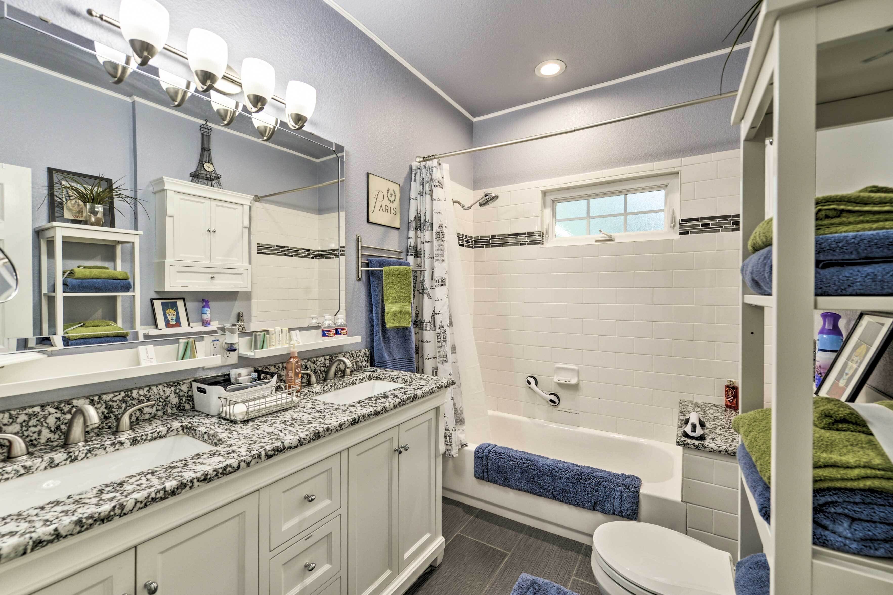 A bathroom with a white vanity, a large mirror, a shower with a curtain, and a toilet.