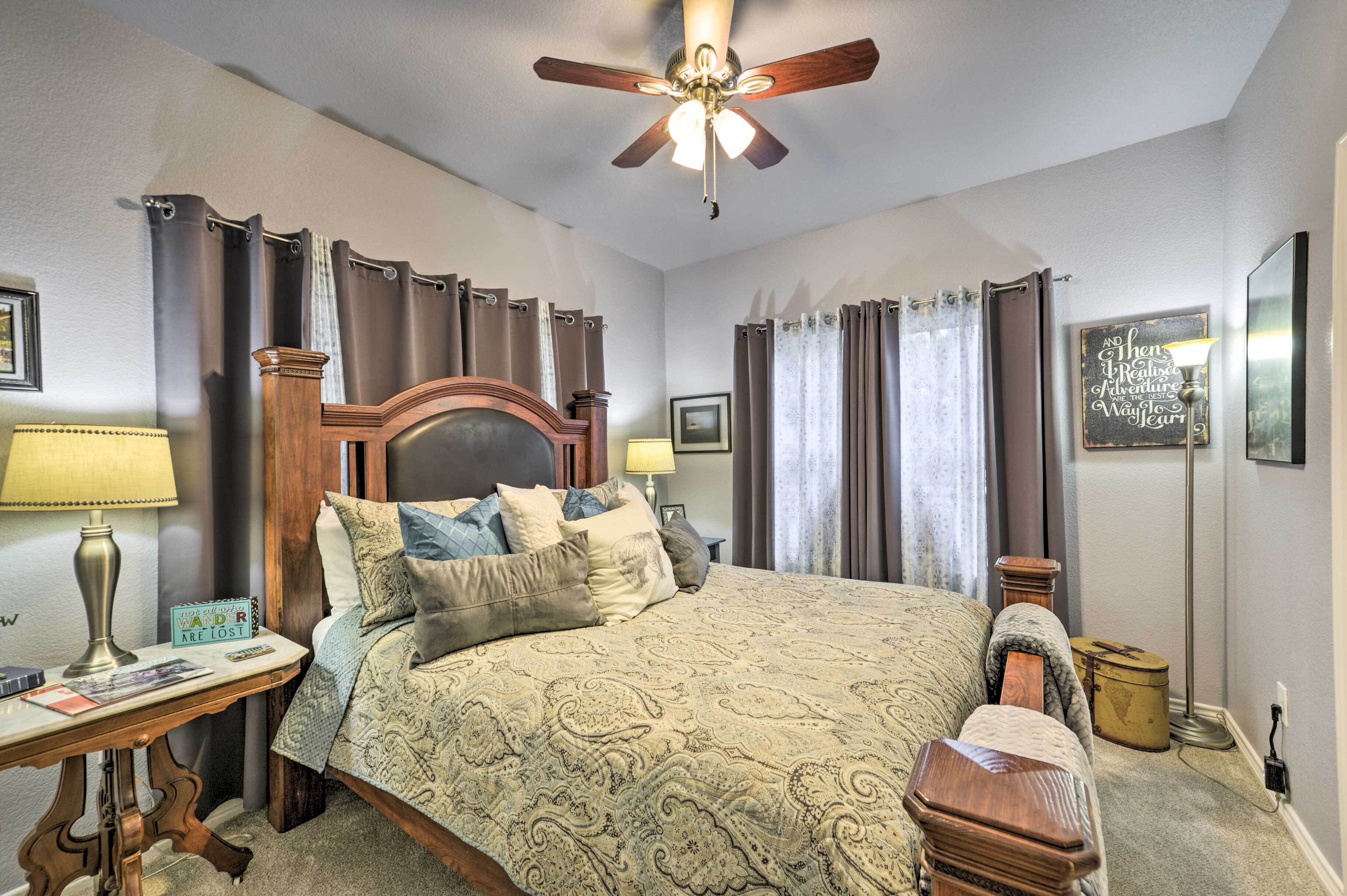 A neatly arranged bedroom with a bed, bedside tables, a ceiling fan, and curtains.