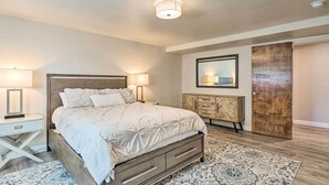 A bedroom with a bed, bedside tables, a dresser, a mirror, and a door. - Pet-friendly CO Springs Home w/ Koi Pond & Patio (Colorado Springs)