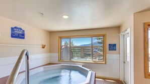 Un jacuzzi con una escalera metálica, una ventana con vistas y un cartel que indica el horario de uso.