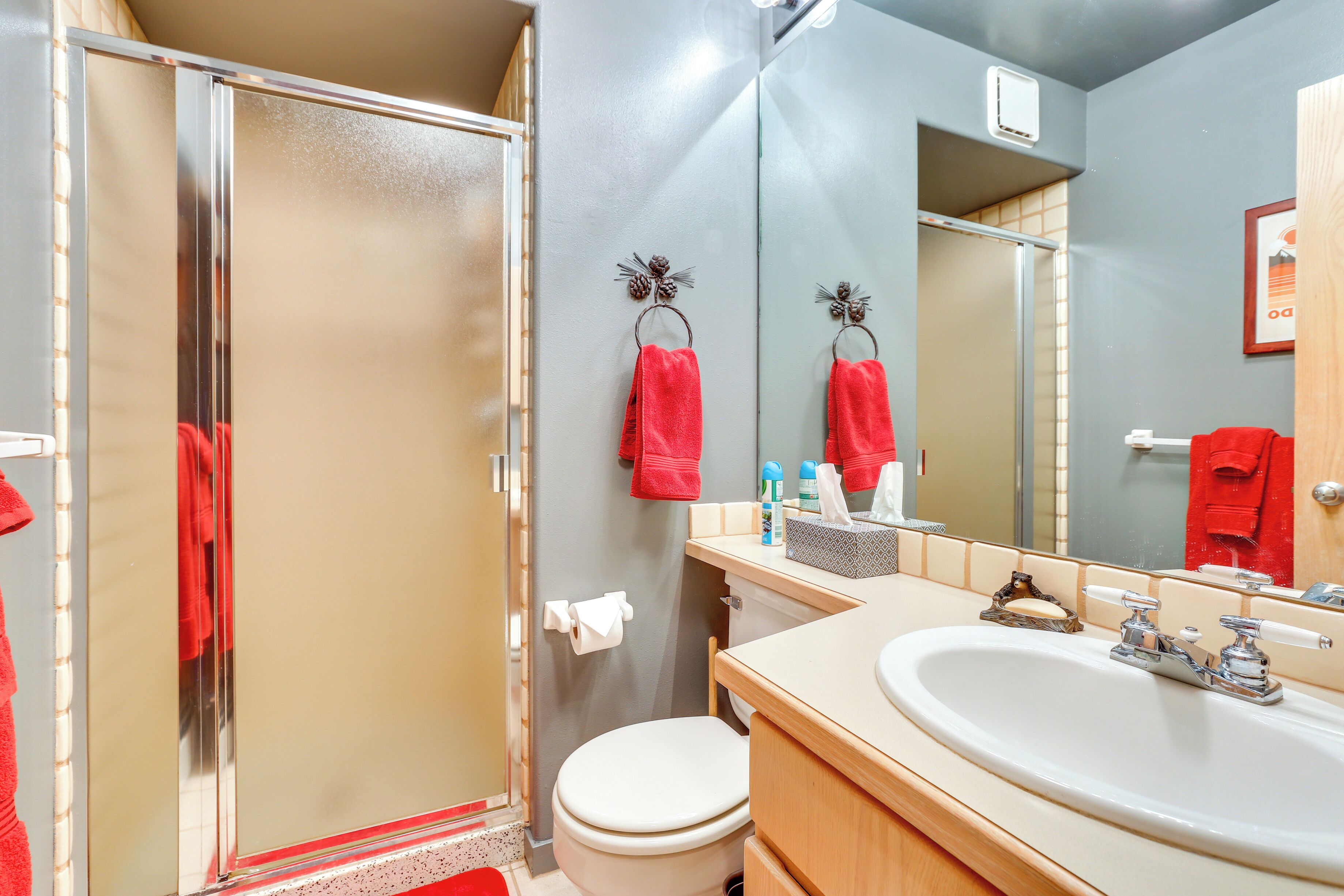 A bathroom with a shower, toilet, sink, and mirror.