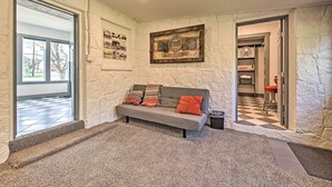 Ein gemütlicher Wohnbereich mit einem grauen Sofa, gemusterten Kissen und einem gerahmten Bild an der Wand.