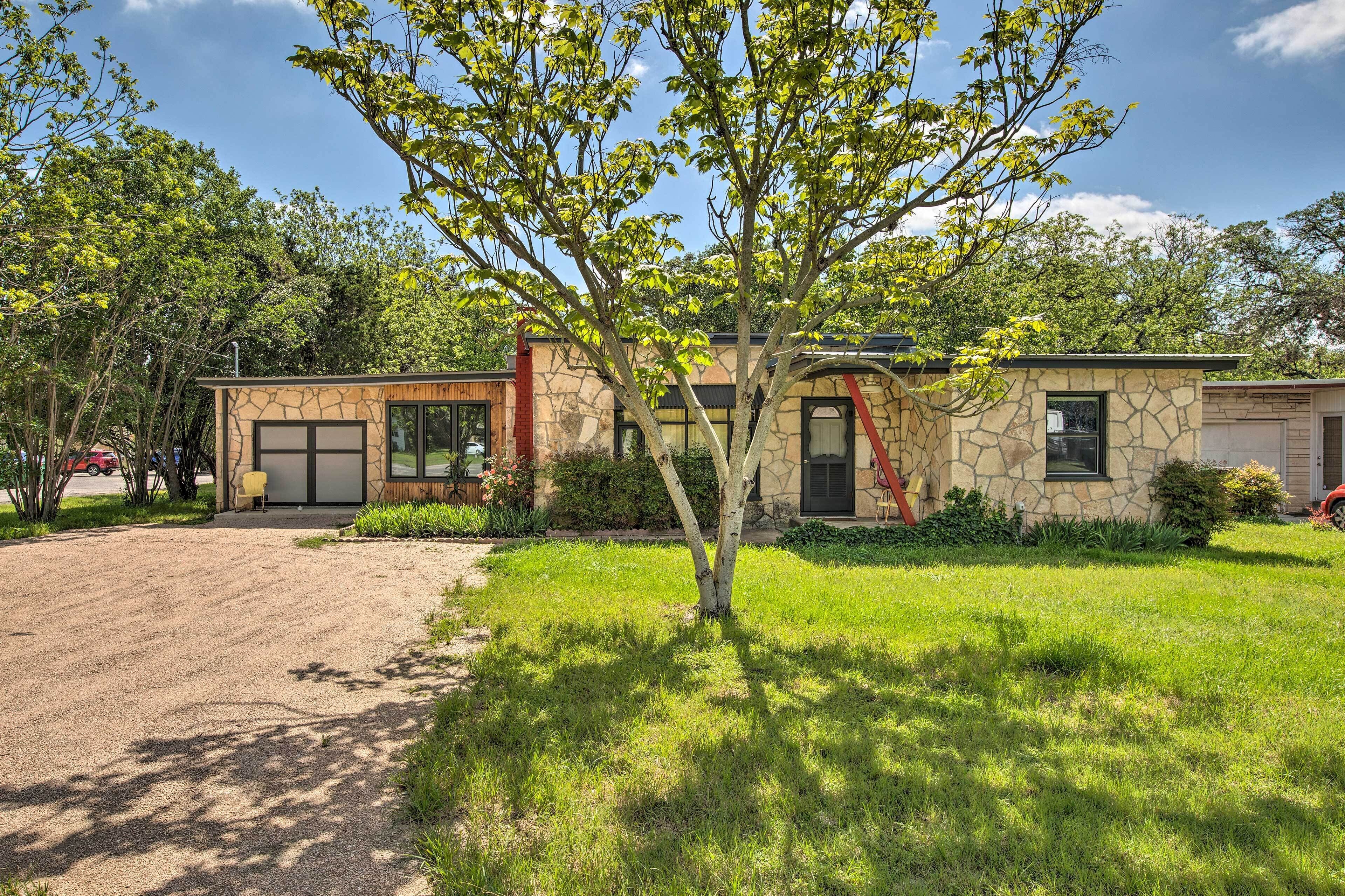 Een modern huis met een gevel van natuursteen, een oprit en een verzorgd gazon.