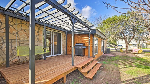 Ein überdachter Außenbereich mit Holzterrasse, Grill und einer Pergola.