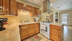 A kitchen with wooden cabinets, a stove, and a sink. - San Antonio House w/ Private Pool, Spa & Grill (San Antonio)