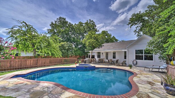 A swimming pool with a stone border, surrounded by a wooden deck and a house. - San Antonio House w/ Private Pool, Spa & Grill (San Antonio)