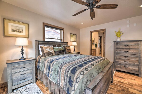 A bedroom with a large bed, wooden nightstands, a ceiling fan, and a dresser.