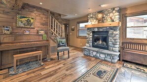 Un salon chaleureux avec une cheminée en pierre, un plancher en bois, un banc et un escalier.