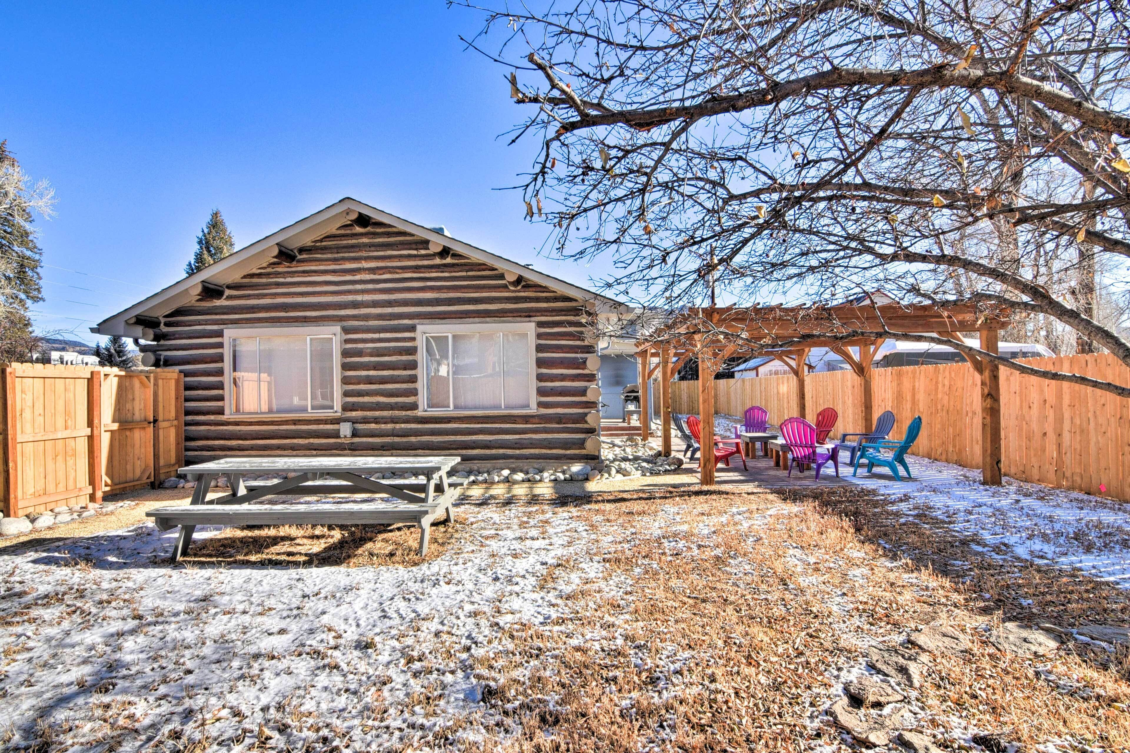 Une cabane en rondins dotée d’une terrasse en bois et d’un espace salon extérieur.