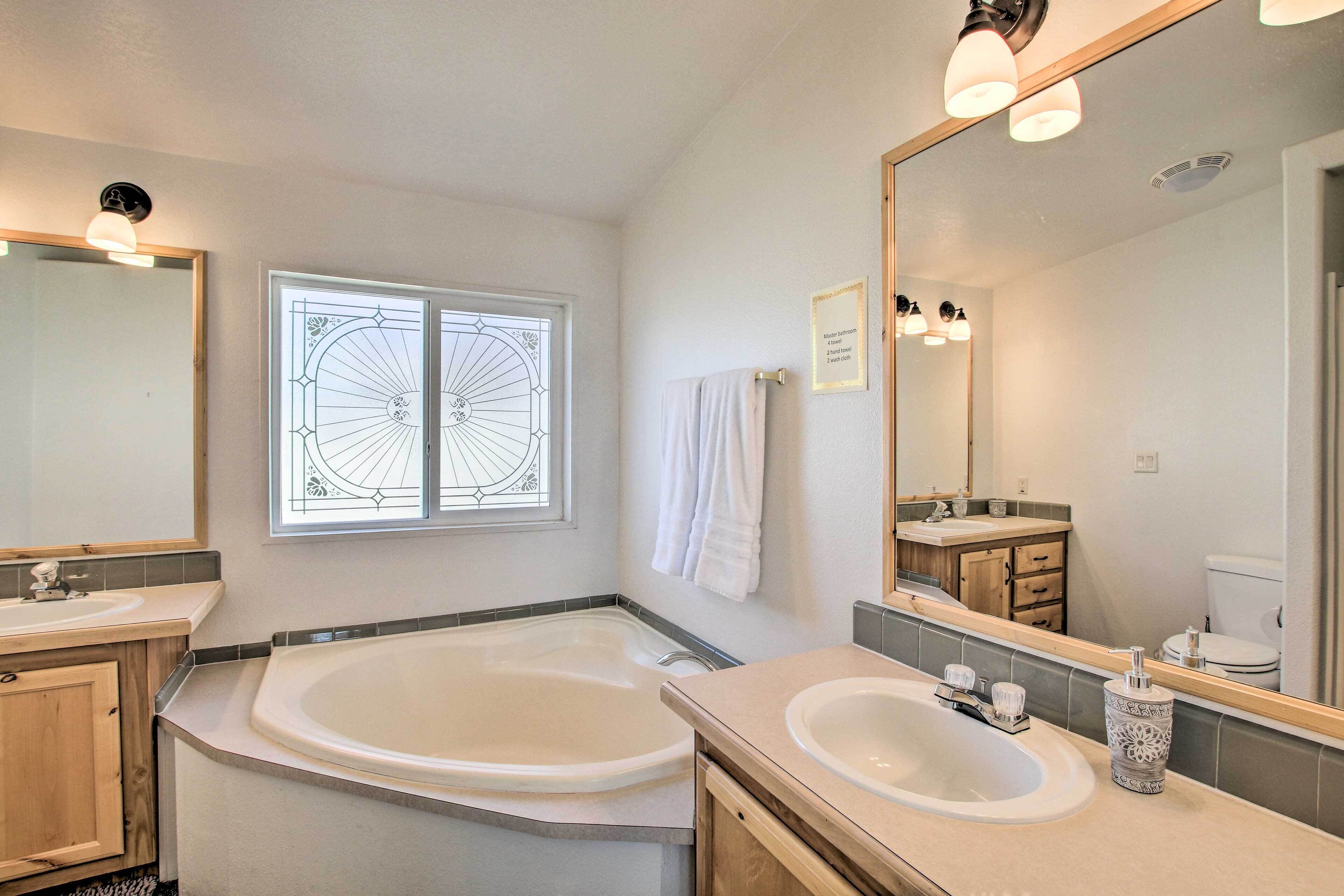 A modern bathroom with a large bathtub, two sinks, and a large mirror.