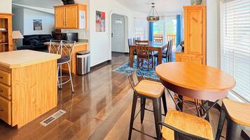 A modern kitchen with wooden cabinets, a dining area with a round table and chairs, and a visible door leading to another room.