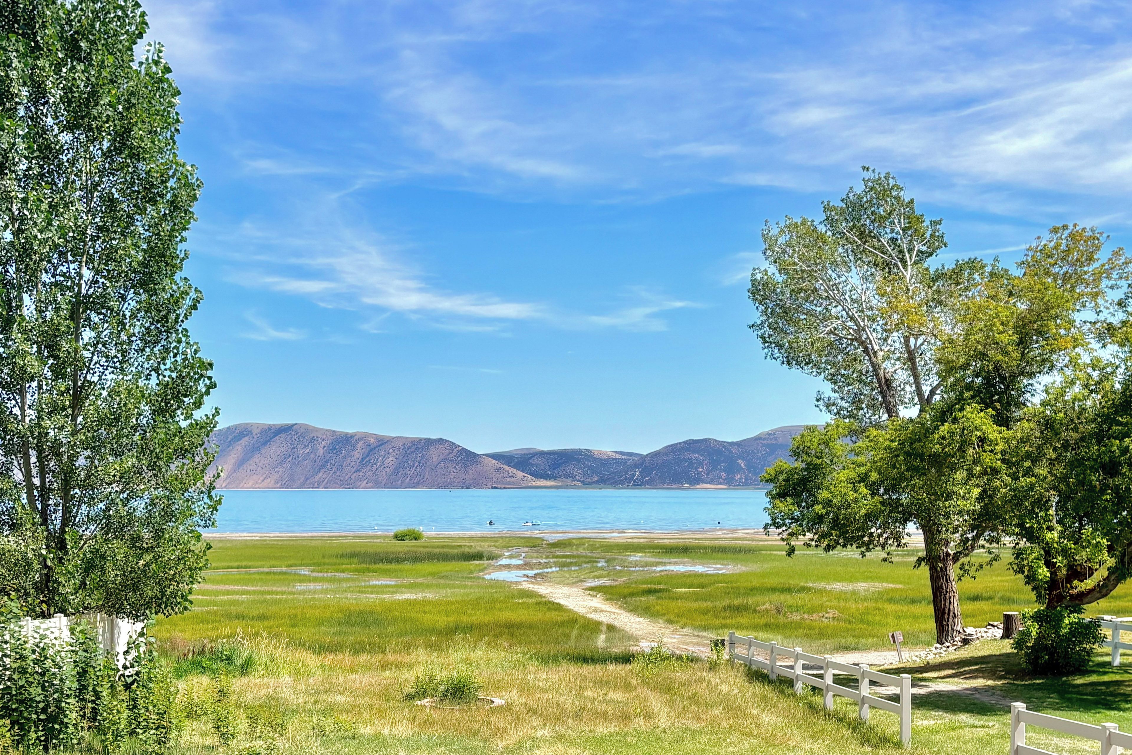 A natural landscape with a clear sky, a body of water, and mountains in the distance.