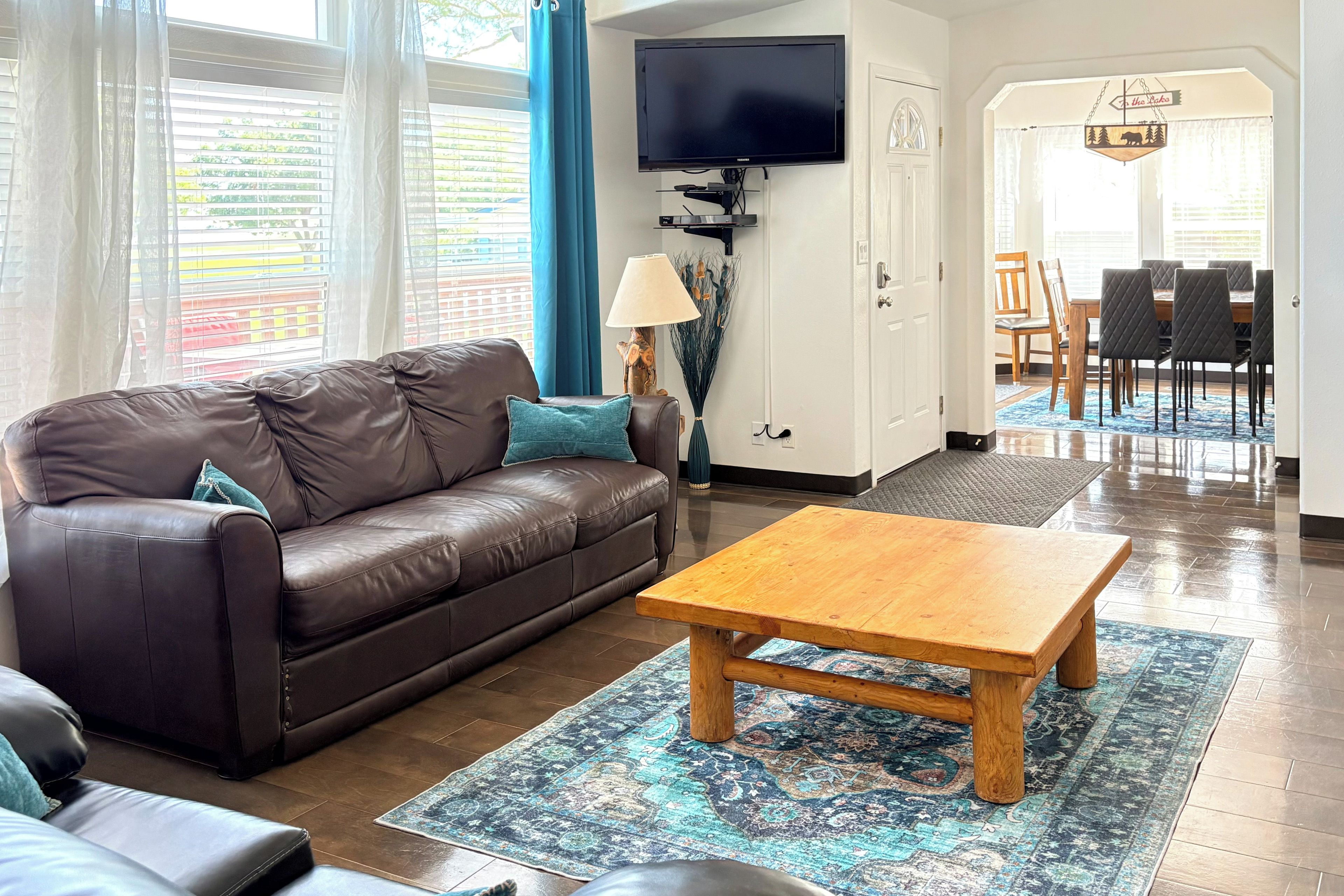 A living room with a brown leather sofa, a wooden coffee table, and a patterned rug.