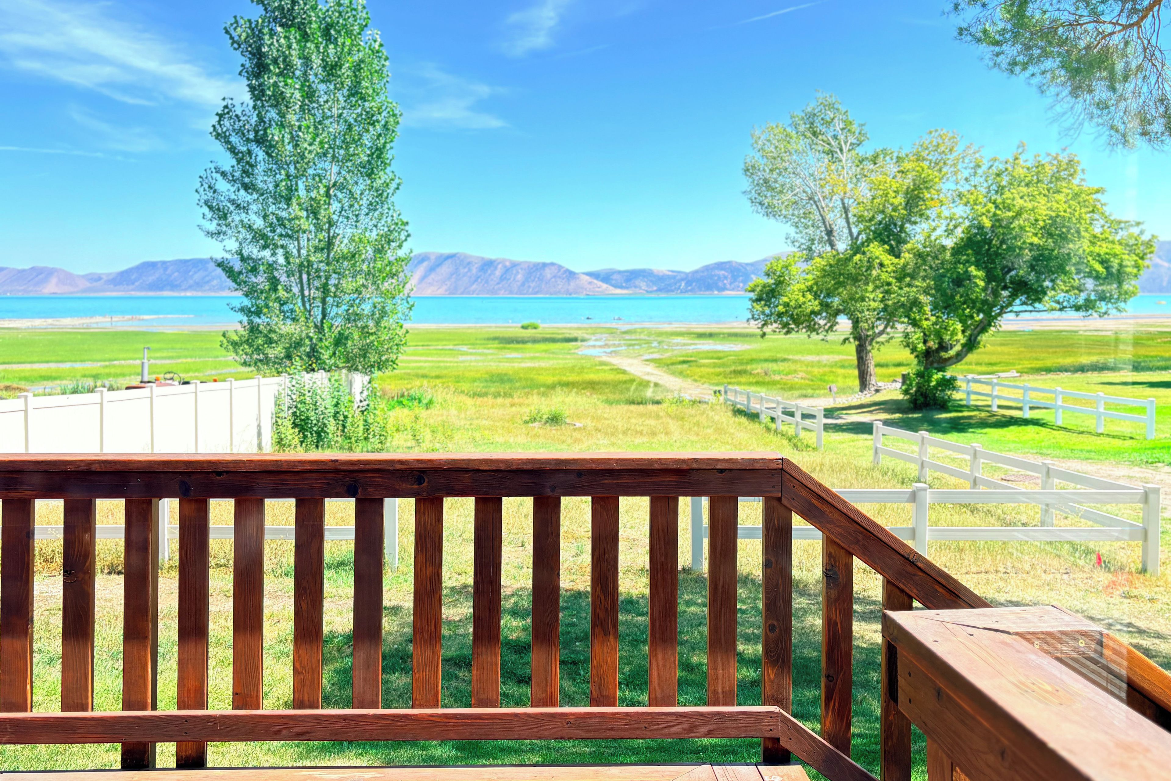Una terraza de madera con vistas a un lago y montañas.