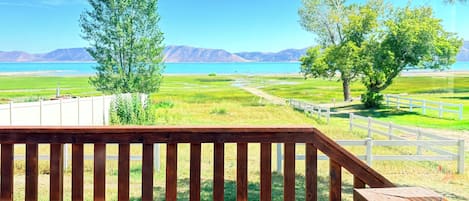 Una terraza de madera con vistas a un lago y montañas.