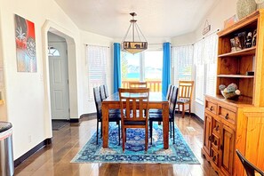 A dining area with a wooden table and chairs, a patterned rug, and a view of the outdoors.