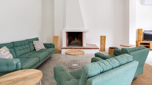 A modern living room with a fireplace, green sofas, and a round wooden coffee table. - 3320 Villa Fiorezza - 3 PT by Barbarhouse (Maruggio)