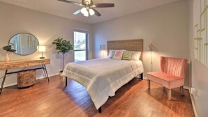 A bedroom with a bed, a chair, a desk, a mirror, and a ceiling fan. - Modern Fayetteville Home < 1 Mi to U of A! (Fayetteville)
