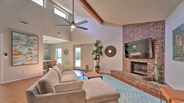 A spacious living room with a large sectional sofa, a fireplace, and a television mounted on the brick wall. - Modern Fayetteville Home < 1 Mi to U of A! (Fayetteville)