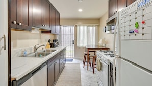A kitchen with wooden cabinets, a sink, a stove, and a refrigerator. - Cozy San Diego Escape w/ Yard, Near Beaches! (San Diego)