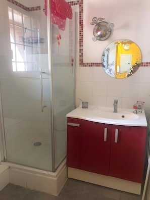 A bathroom with a glass shower enclosure, a sink with a mirror, and red cabinets. - A bright and sunny one-bedroom apartment with a private terrace and a beautiful, unobstructed view. (Aix-en-Provence)