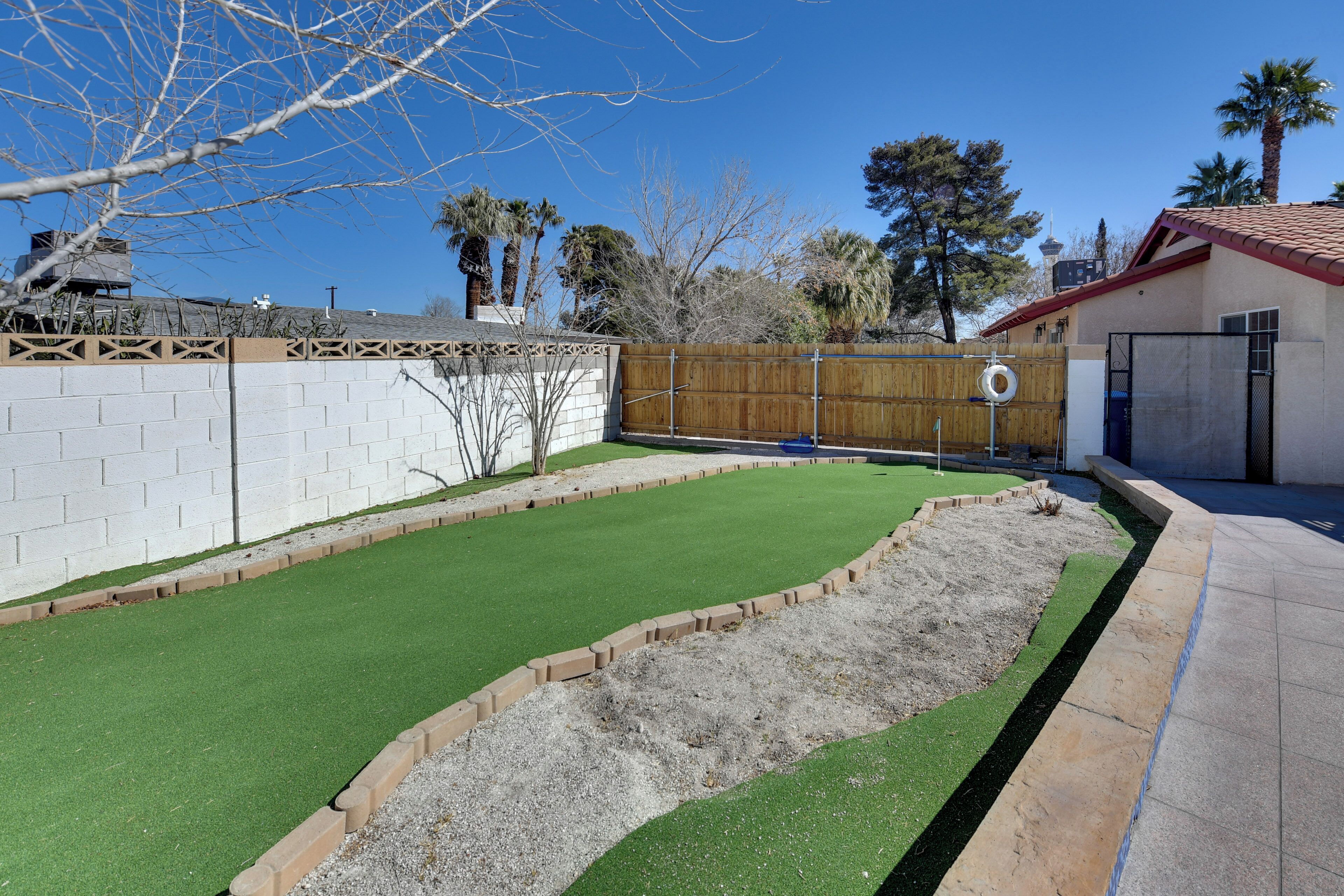 A backyard with artificial grass, a wooden fence, and a brick wall.